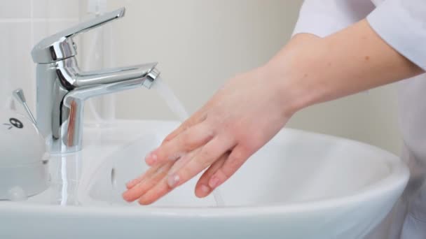 Κοντινό πλάνο της γυναίκας γιατρό σωστά και καλά πλένει τα χέρια του με αφρό σαπουνιού κοντά στην συμπεριλαμβανόμενη βρύση νερού. Ιατρικός ειδικός πλένει κάθε δάχτυλο, απολυμαίνει τα χέρια στο νοσοκομείο. - Πλάνα, βίντεο