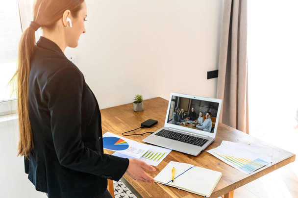 A young woman connects via video with coworkers - Foto, Imagen