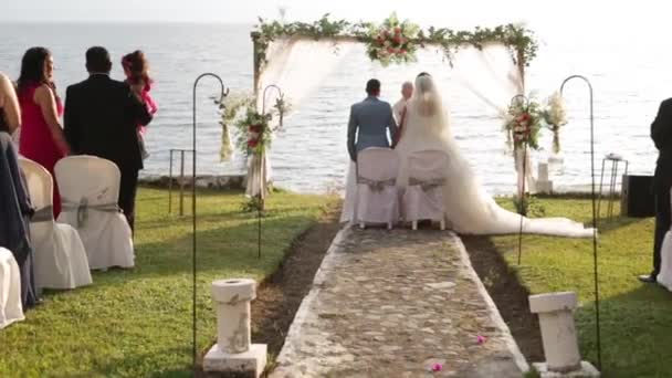 para bierze ślub o zachodzie słońca nad jeziorem atitlan w Gwatemali, naturalny ślub otoczony kwiatami, trawą i jeziorem oraz krajobrazem wulkanu - Materiał filmowy, wideo