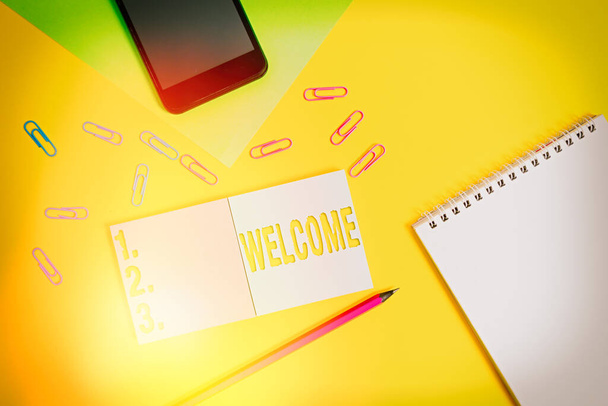Writing note showing Welcome. Business photo showcasing instance or manner of greeting someone in polite or friendly way Square blank sticky notepads pencil smartphone sheet color background. - Photo, Image