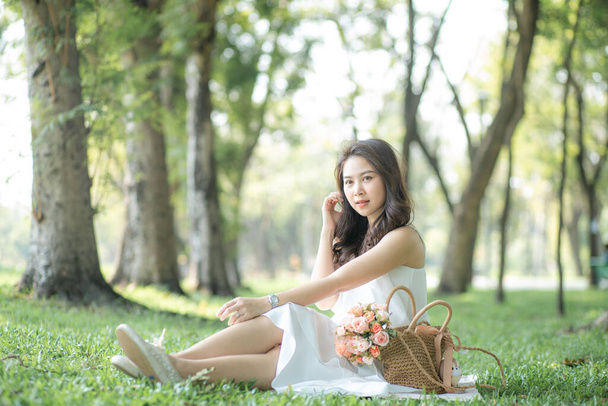 Attractive asian beautiful women sitting on green grass talking smartphone in city park. - Foto, Imagen