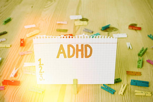 Conceptual hand writing showing Adhd. Business photo showcasing Mental health disorder of children Hyperactive Trouble paying attention Colored crumpled papers wooden floor background clothespin. - Photo, image