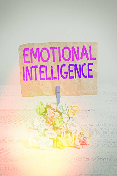Text sign showing Emotional Intelligence. Conceptual photo Self and Social Awareness Handle relationships well Reminder pile colored crumpled paper clothespin reminder white wooden space. - Photo, Image