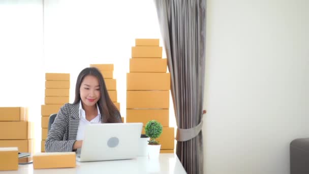 πλάνα από όμορφη Ασιάτισσα γυναίκα που εργάζεται στο σπίτι με δέματα σε κουτιά - Πλάνα, βίντεο