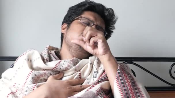 Smutny młody człowiek z grypą zawiniętą w ciepły koc - Materiał filmowy, wideo