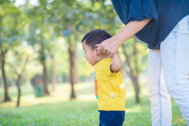Мальчик первый шаг держит мать в городском парке
 - Фото, изображение