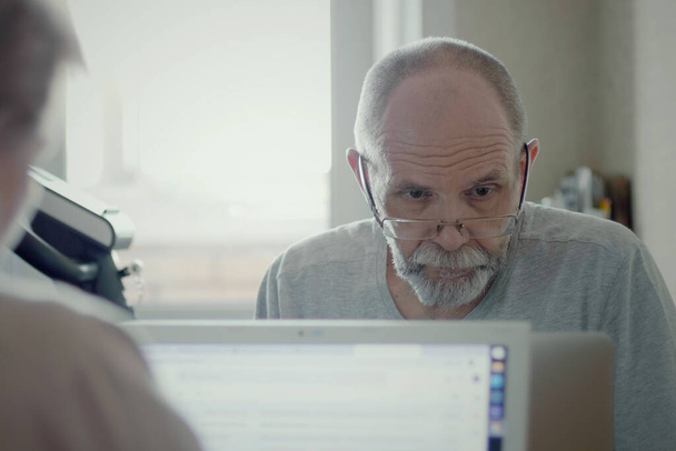 Портрет взрослого лысого мужчины с седыми волосами, работающего дистанционно с ноутбуком в домашнем офисе, коронавирусный карантин, самоизоляция, оставайтесь дома
 - Фото, изображение