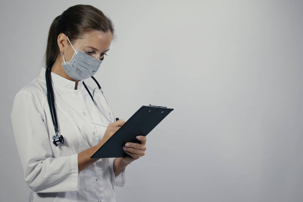 Femme médecin dans un manteau médical blanc médecin généraliste avec un phonendoscope prendre rendez-vous patients calendrier dans un bloc-notes avec stylo
 - Photo, image
