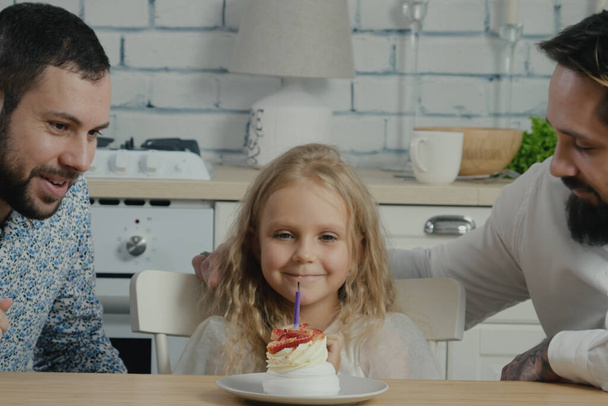 Kafkasyalı doğum günü kızı küçük beyaz pastaya mum üflüyor homoseksüel ailelerle kutlama partisi yapıyor. Evde aile kutlaması - Fotoğraf, Görsel