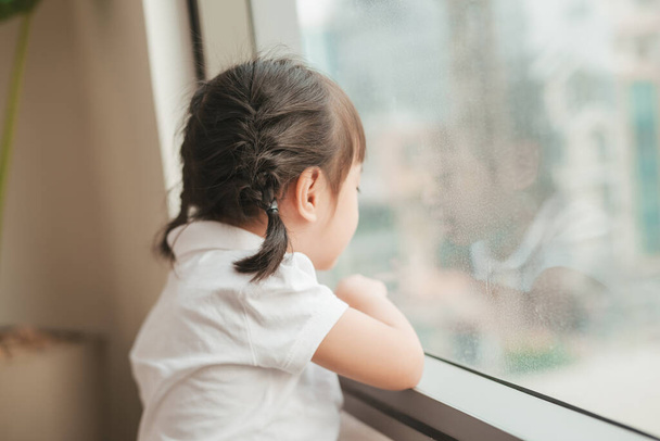 Visszapillantás aranyos kislány néz ki az ablakon - Fotó, kép