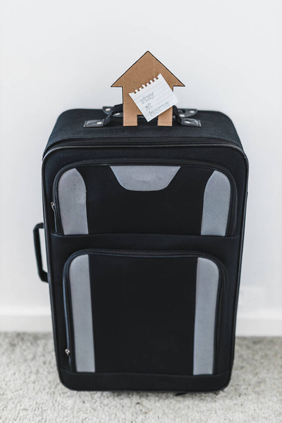 isolation and travel restrictions to flatten the curve against the covid-19 virus outbreak, suitcase with Stay Home message and house icon on top of it - Foto, immagini