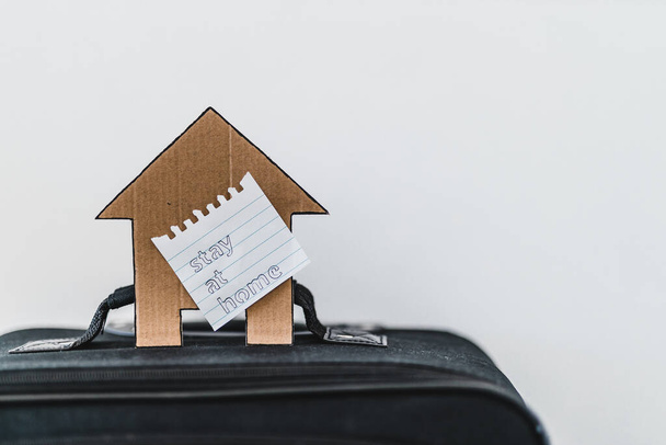 isolation and travel restrictions to flatten the curve against the covid-19 virus outbreak, suitcase with Stay Home message and house icon on top of it - Fotoğraf, Görsel