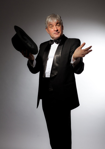 Elegant man in tuxedo and hat on a gray background - Foto, Imagen