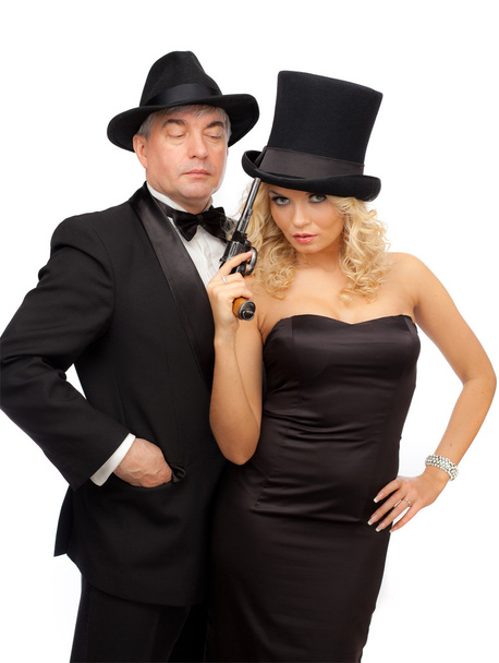 Man and woman in elegant suits and hats with a revolver - Photo, Image