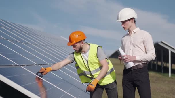Businessman and worker are checking solar batteries together outside - Filmagem, Vídeo