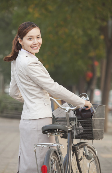 Mulher de negócios de pé com uma bicicleta
 - Foto, Imagem