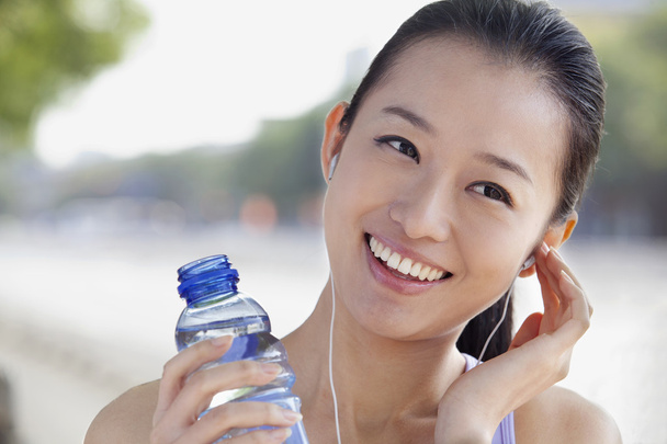 γυναίκα με εμφιαλωμένο νερό, ακούγοντας μουσική - Φωτογραφία, εικόνα