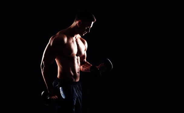Strong, fit and sporty bodybuilder man over black background. Sport and fitness concept. - 写真・画像