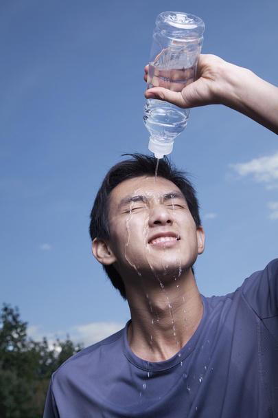 άνθρωπος ρίχνει εμφιαλωμένο νερό πάνω από το κεφάλι του - Φωτογραφία, εικόνα