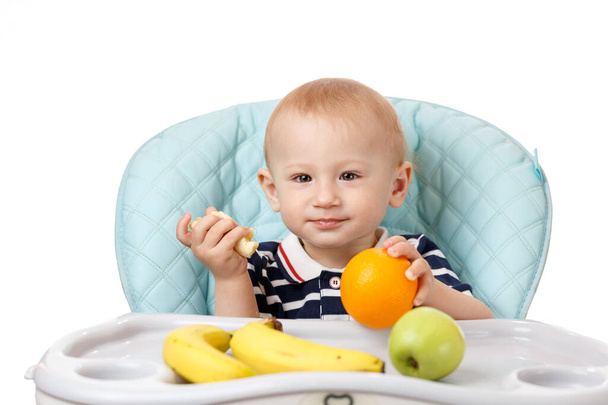 Cheerful little boy eating fresh bananas on a white background - Foto, Imagen