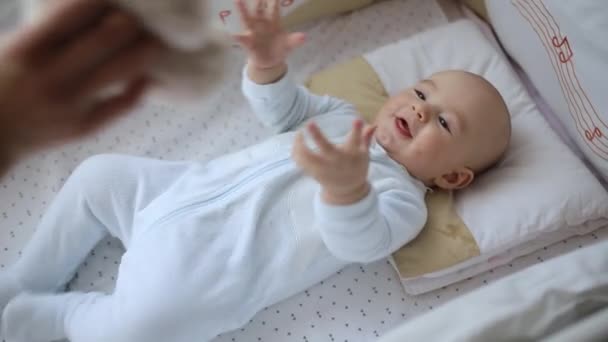 Cute little baby bawi się zabawką w łóżeczku - Materiał filmowy, wideo