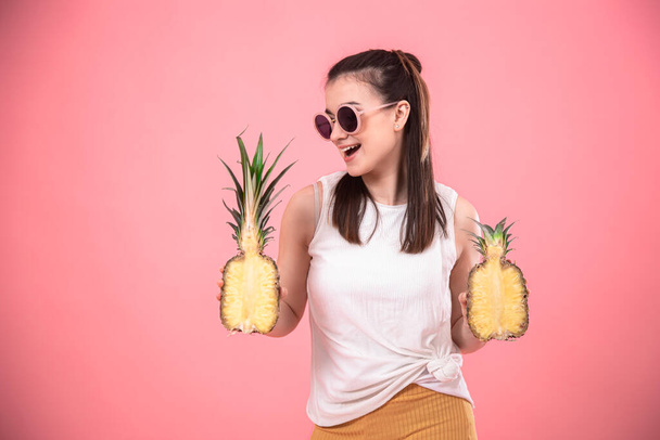 portrait of a stylish woman on a pink background with pineapples in her hands. Summer concept. - Zdjęcie, obraz