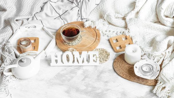 Gemütliches Stillleben zu Hause mit einer Tasse Tee und einem Wasserkocher. Holzinschrift zu Hause auf dem Tisch. - Foto, Bild