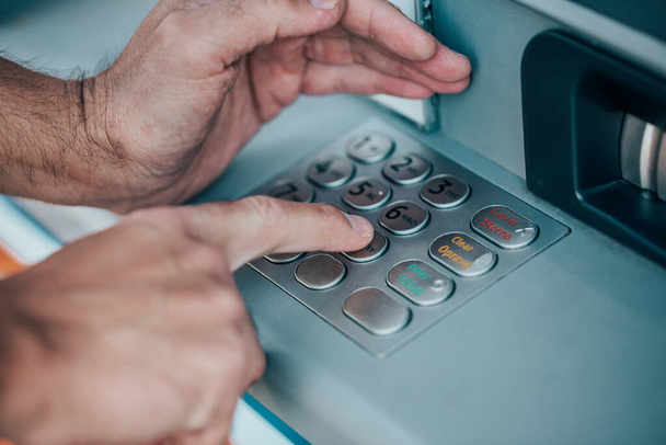 Homem que introduz um código PIN para o seu cartão de crédito num multibanco, retirando dinheiro, conceito de finanças
 - Foto, Imagem