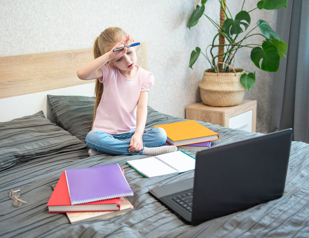 Kaukasische Mädchen, die im Bett sitzen und online am Laptop lernen. Heimschule, Online-Bildung, häusliche Erziehung, Quarantäne, Coronavirus-Konzept. - Foto, Bild