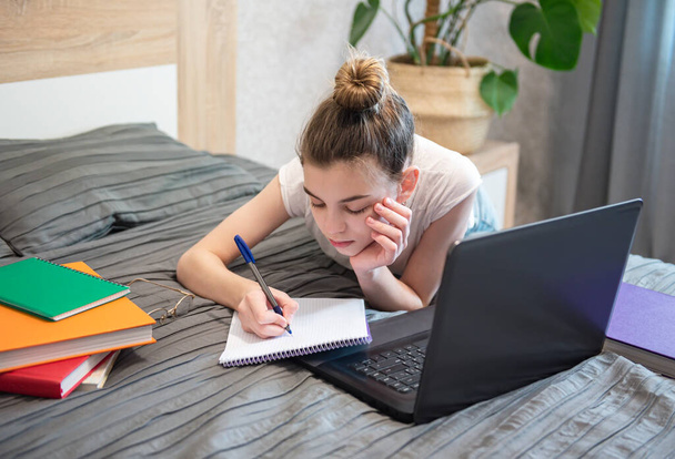 Genç kız evde dizüstü bilgisayar kullanıyor. Uzaklık öğrenme kavramı.  - Fotoğraf, Görsel