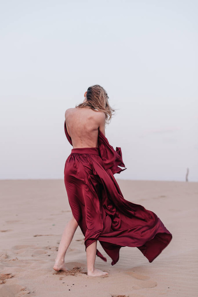 A girl with a fabric is standing in the wind in the desert - Fotografie, Obrázek