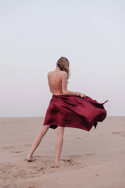 A girl with a fabric is standing in the wind in the desert - Fotografie, Obrázek