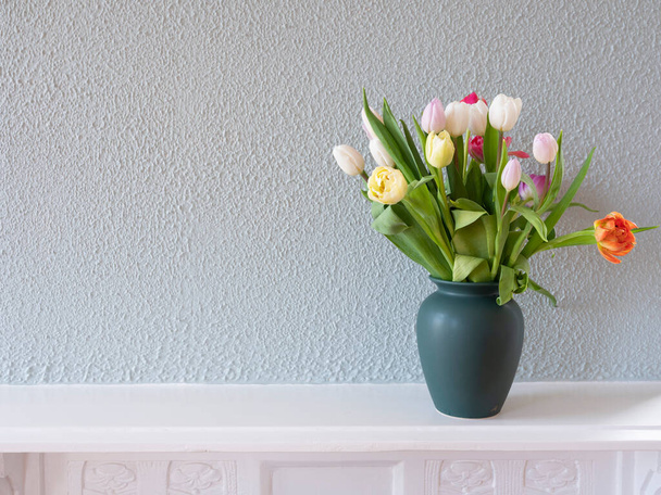 白い背景に隔離された緑の花瓶にチューリップ花束 - 写真・画像