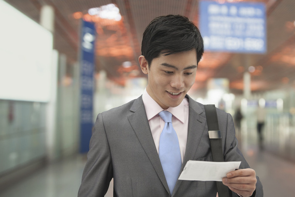 Businessman looking at ticket at the airport - Φωτογραφία, εικόνα