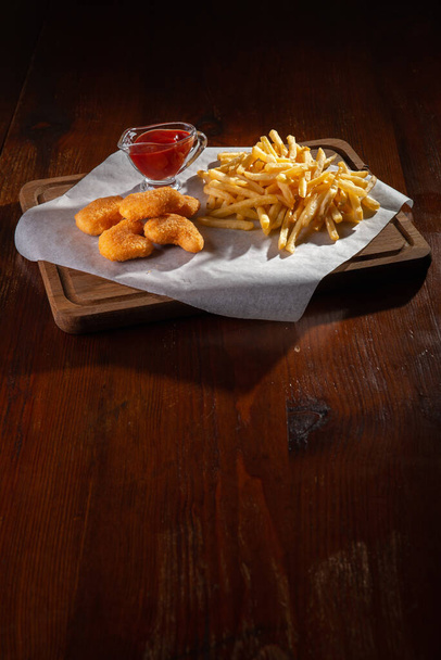 Nuggets french fries and sauce on a dark wooden background - Foto, immagini