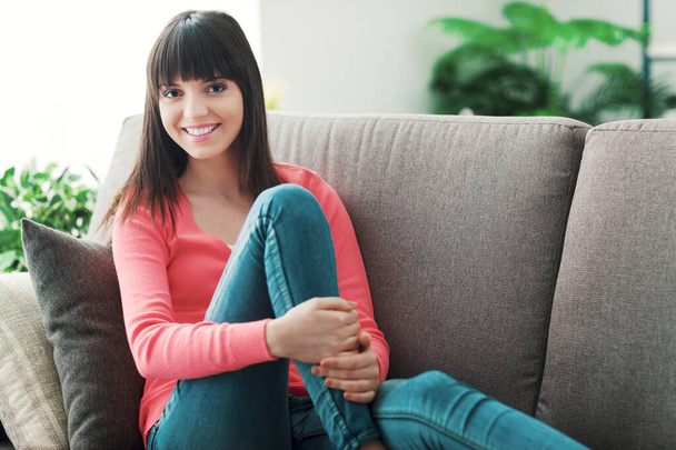 Smiling attractive woman at home, she is sitting on the sofa, relaxing and posing - Photo, Image