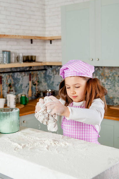 Lány a konyhában gyúrja a tésztát. - Fotó, kép