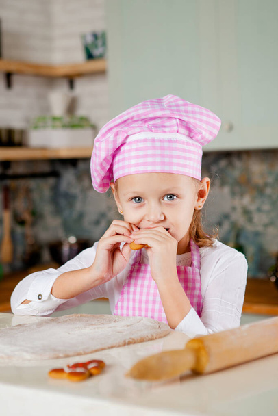 Girl in the kitchen kneads dough for gingerbread - Фото, зображення