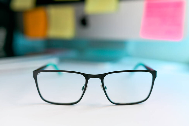 Close up image of black and green eyeglasses on the desk with blur background - Photo, Image