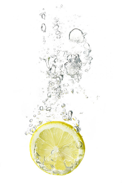 lemon slice dropped into water with bubbles - Foto, Imagen