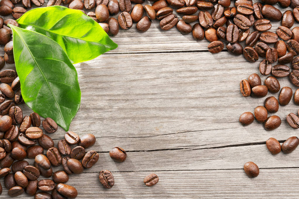 Kaffeebohnen und Blätter auf Holzgrund - Foto, Bild