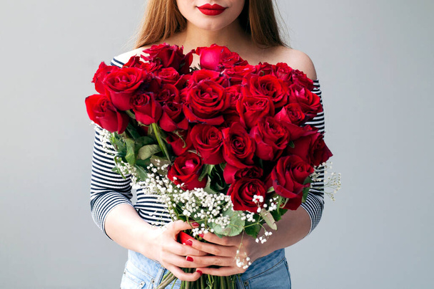 Smiling girl with bouquet of red roses - Photo, image