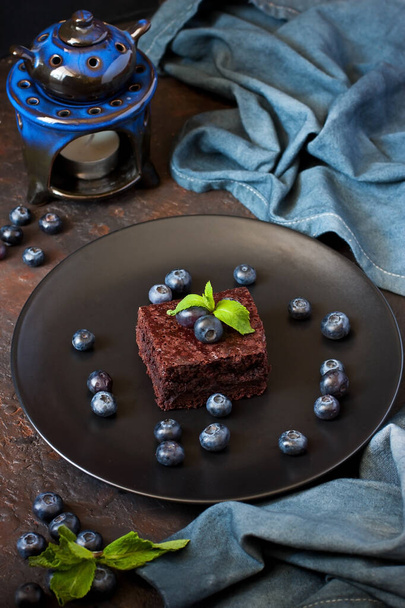 Delicious homemade chocolate brownie with blueberry and mint on dark stone background. Selective focus. Small raw chocolate cakes - Foto, Imagem