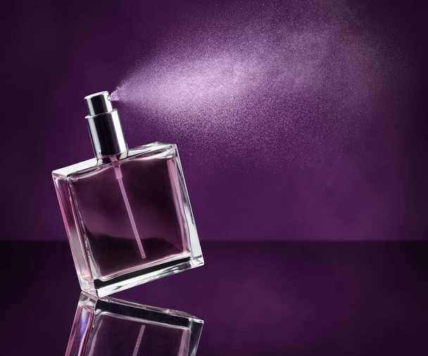 perfume botella pulverización sobre fondo púrpura oscuro
 - Foto, Imagen