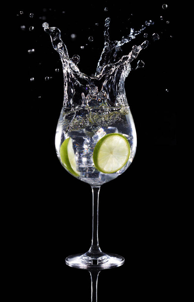gin tonic cocktail spatten geïsoleerd op zwarte achtergrond - Foto, afbeelding