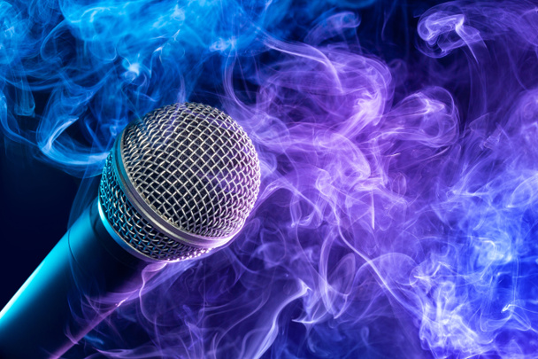 Nahaufnahme eines Mikrofons, das in einen violett-bläulichen Qualm gehüllt ist  - Foto, Bild