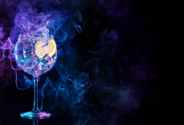 gin tonic cocktail splashing in blue and purple smoky background	 - Foto, afbeelding