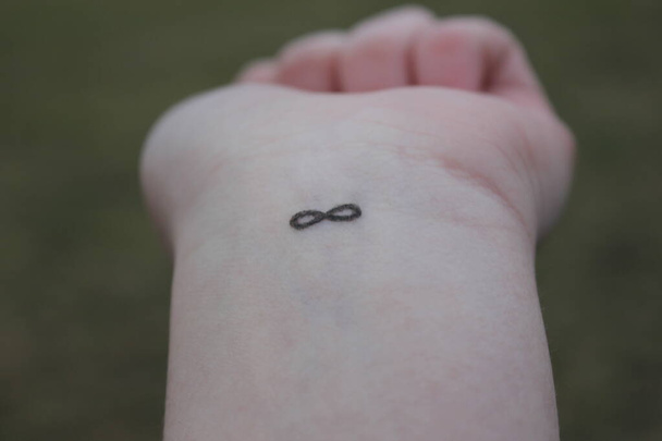 primer plano del brazo con un símbolo de infinito tatuado en su muñeca. signo de infinito en la mano. concepto de amor sin fin
 - Foto, Imagen