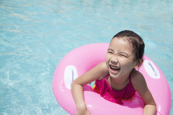 ピンク チューブ付きのプールで泳いでいる少女 - 写真・画像