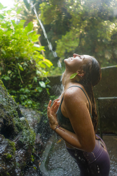 holidays adventure lifestyle portrait - young beautiful and happy woman taking natural shower from waterfall in the jungle enjoying the nature carefree and fresh in wellness concept - Фото, изображение